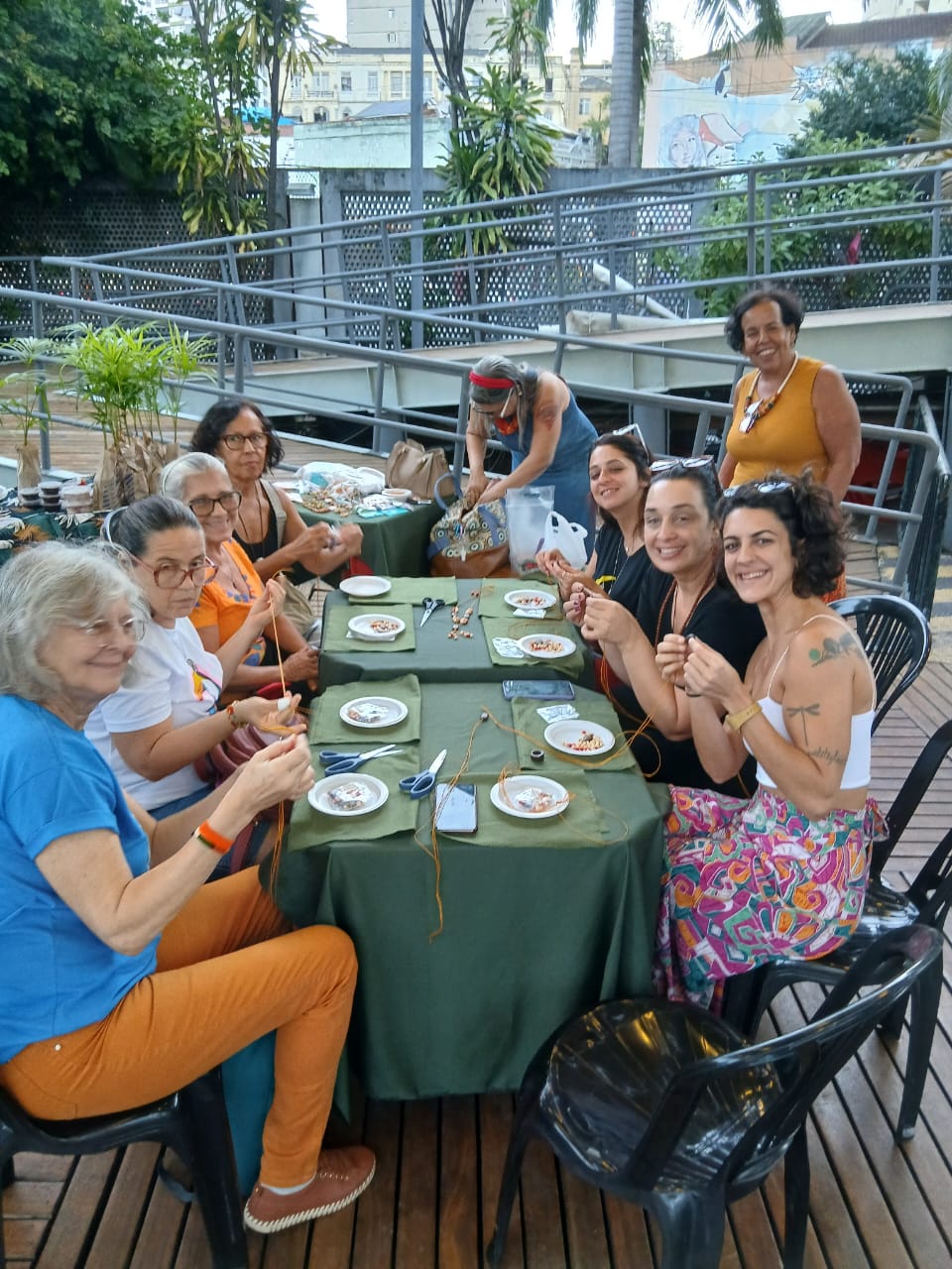 Roda de mulheres confeccionando colares com sementes de juçara no deck do Circo Voador