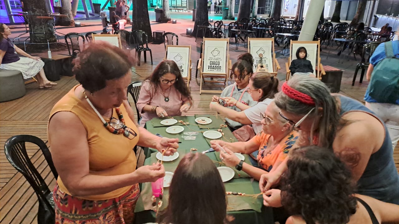 Mesa da oficina de artesanato com sementes de juçara em andamento no Circo Voador