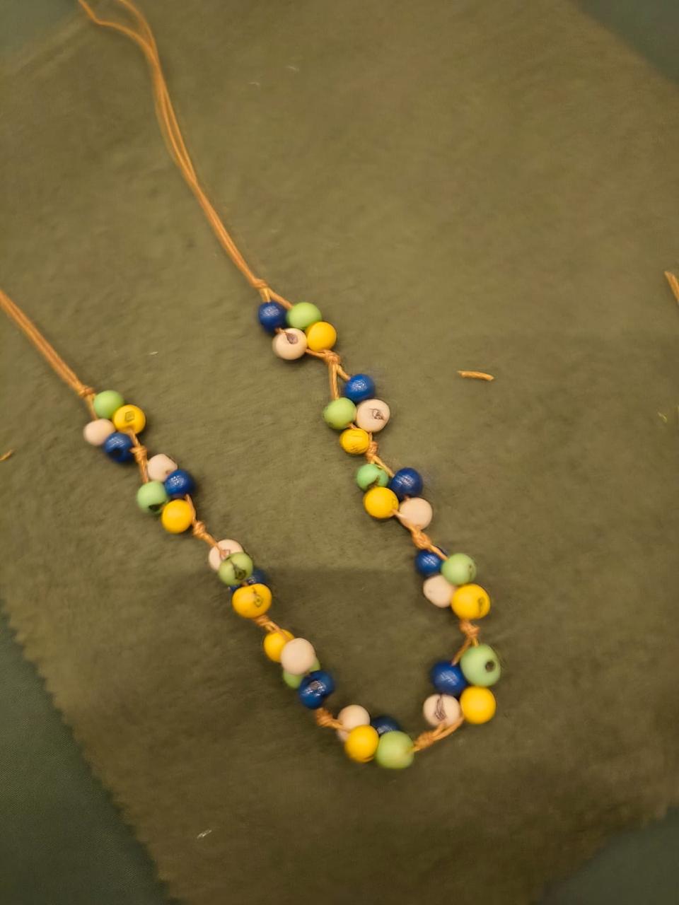 Colar artesanal feito com sementes de juçara coloridas em verde, azul, amarelo e branco